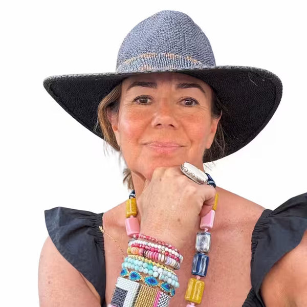 Woman wearing a wide-brimmed hat and colorful jewelry on a white background